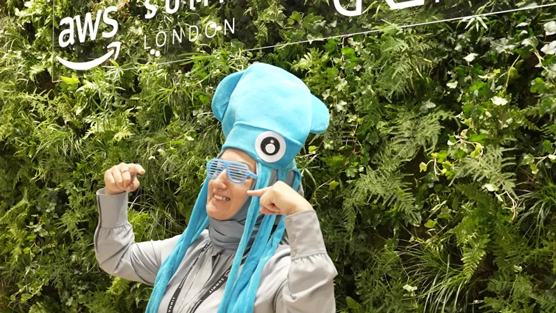 A visitor in a turquoise squid costume in front of a green wall