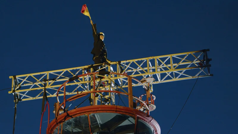 A performer signalling with semaphore flags from the ship’s gantry